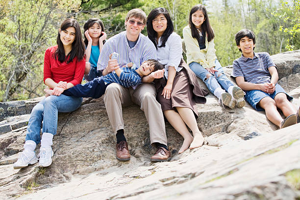 Family sitting together on rocky ledge stock photo