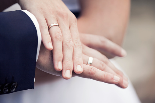 Close-up of the bride and groom's hands, with wedding rings on their fingers.