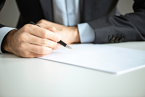 Close up of an unrecognizable businessman signing contract paper.