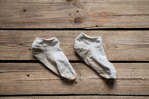 Dirty short white socks lie on the wooden floor of the house close-up