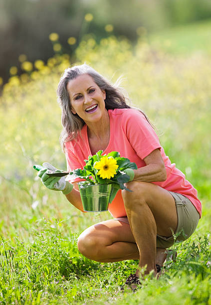 sênior mulher em campo de flores silvestres rindo - planting clothing gray hair human age - fotografias e filmes do acervo