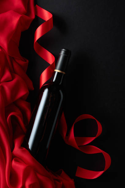 istock Bottle of red wine with red satin on a black background. 1479143210