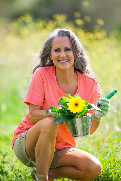 mulher mais idosa ao ar livre com vaso de flor - planting clothing gray hair human age - fotografias e filmes do acervo