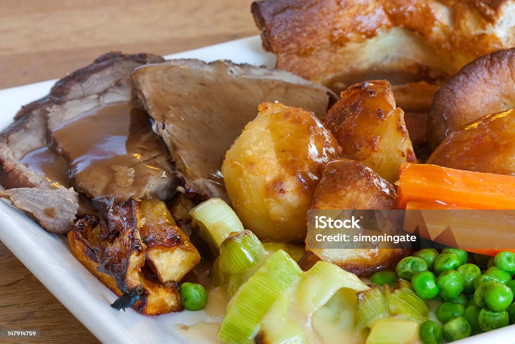 A Sunday roast with pork, potatoes, carrots and peas sunday roast dinner on an old wooden table Roast Dinner Stock Photo