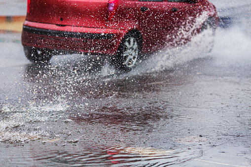 Car drives through puddles and wet asphalt. Rain. Drops. Weather. Water splash. Flood