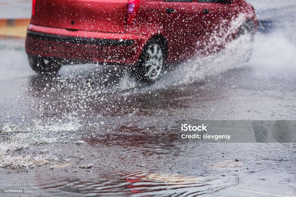 Car drives through puddles and wet asphalt. Rain. Drops. Weather. Water splash. Flood Rainy weather. City Rain Stock Photo