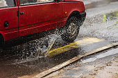 Car drives through puddles and wet asphalt. Rain. Drops. Weather. Water splash. Flood