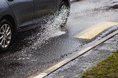 Car drives through puddles and wet asphalt. Rain. Drops. Weather. Water splash. Flood