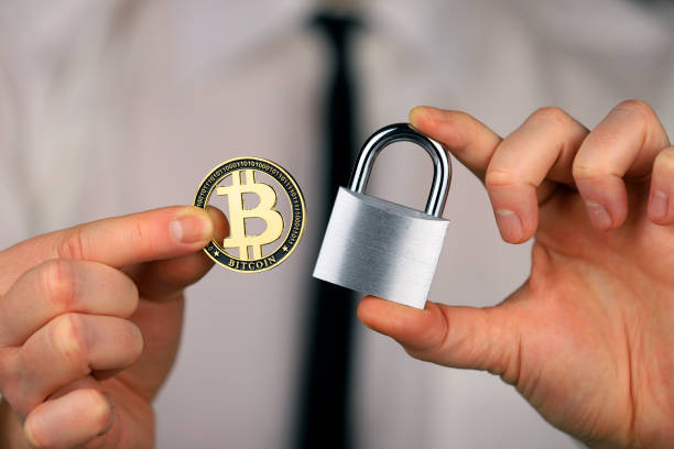 A businessman holds a silver padlock and physical version of bitcoin in his hands. Prohibition of cryptocurrencies, regulations, restrictions or security, protection, privacy stock photo