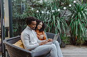 African American young couple enjoying in back tard and using laptop