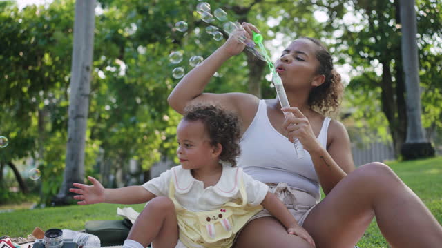 Young mother blowing bubbles with a child in a park