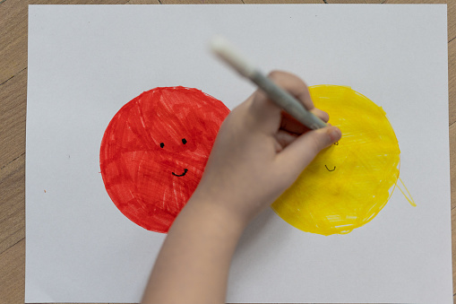 Drawing of a girl on a white sheet. Red and yellow color. close shot.