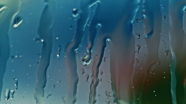 Extreme close up water dripping and spraying on glass