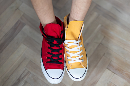 Red and Yellow Sneakers. Wooden parquet in the background. No people. Close shot.