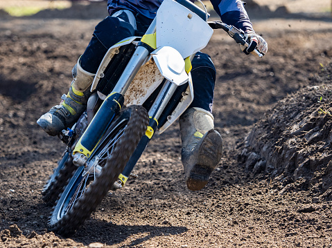 Motorsport photograph of a motocross rider in red sportswear riding his motorcycle on a dirt track in forest