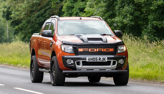 Milton Keynes, Bucks, UK - June 3rd 2022. 2015 orange Ford Ranger pick up truck travelling on an English country road