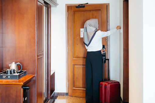 Businesswoman searching for her room at the executive floor of the luxury hotel. opening the door with card-key and inserting into light switch