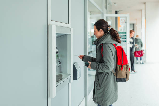 une jeune femme retire de l’argent au guichet automatique de la banque - atm human hand bank real people photos et images de collection