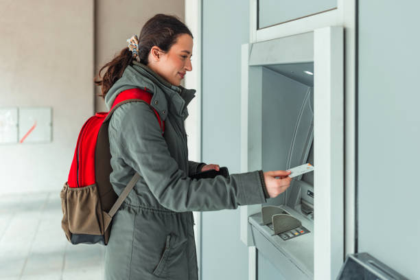 une femme utilise un guichet automatique pour retirer de l’argent pour ses dépenses quotidiennes - atm human hand bank real people photos et images de collection