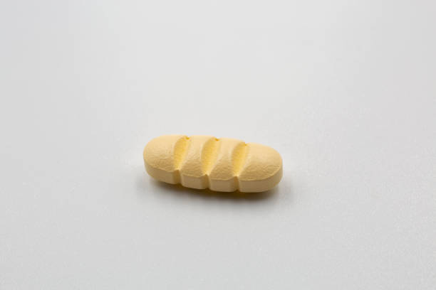 istock Yellow tablet with strips for dividing into four parts closeup. 1479169044