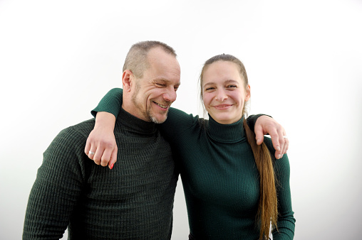 two friends man and a woman hugged standing laughing smiling on a white background green sweaters throwing a hand on their shoulder having fun team colleagues business