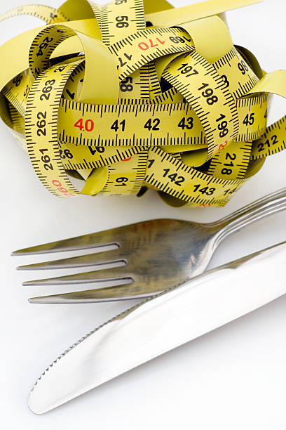 istock Tangled up tape measure next to a fork and knife 147917110