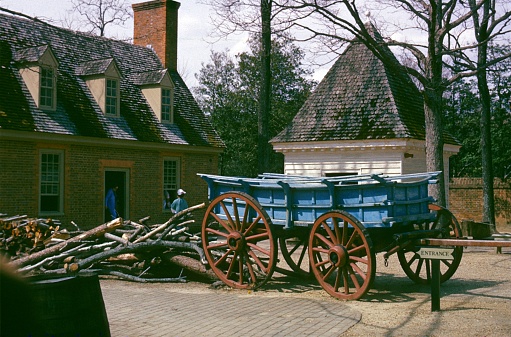 An old wooden cart with large wheels in the farm with forest background