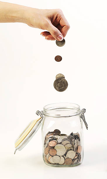istock dropping coins into the glass jar 147917268