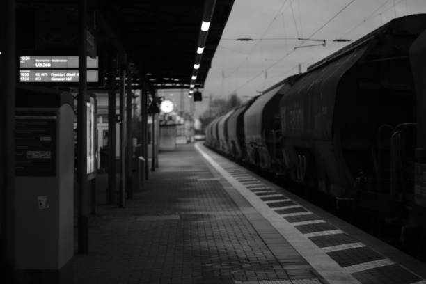 An urban train station scene featuring a stationary train, standing next to a pedestrian sidewalk