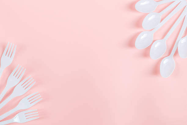 istock White plastic forks and spoons lie on the sides on a light pink background 1479176311