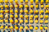 Aerial view of yellow umbrellas on sandy beach at sunset in summer in Sardinia, Italy. Tropical colorful landscape. Travel and vacation background. Top down view from drone. Tropical pattern. Concept
