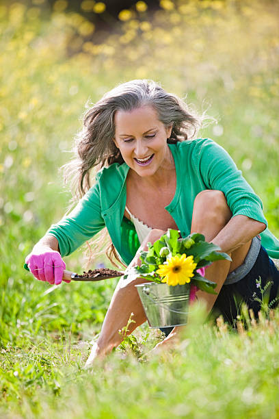 sênior mulher ao ar livre com flores silvestres - planting clothing gray hair human age - fotografias e filmes do acervo