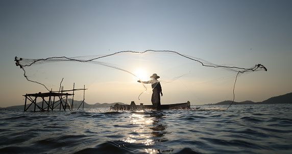 Lifestyle of  fisher man on boat fishing by throwing fishing net, Silhouette  fisherman throwing net hunt fish from reservoir
