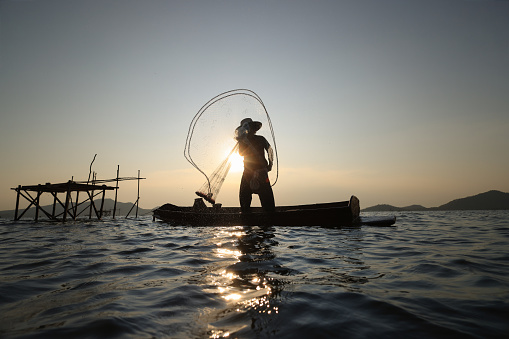 Lifestyle of  fisher man on boat fishing by throwing fishing net, Silhouette  fisherman throwing net hunt fish from reservoir