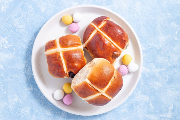 Traditional easter food hot cross buns on white plate with chocolate candy eggs, horizontal, top stock photo