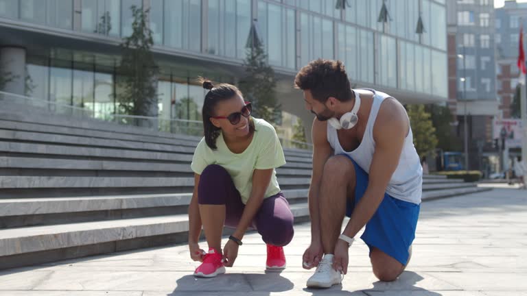 Diverse couple lacing shoes before training outdoors