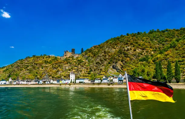 Katz Castle and Sankt Goarshausen seen from a cruise boat on the Rhine with a German flag