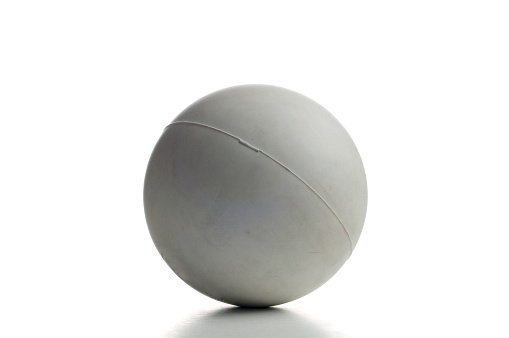 A gray lacrosse ball over white with small shadow