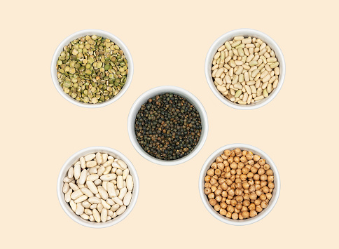 Various legumes, top view with beige background