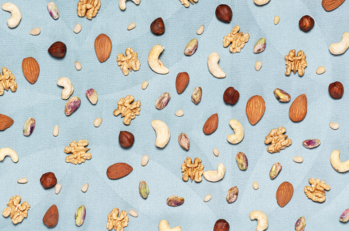 Top view on assorted nuts scattered on a blue tablecloth