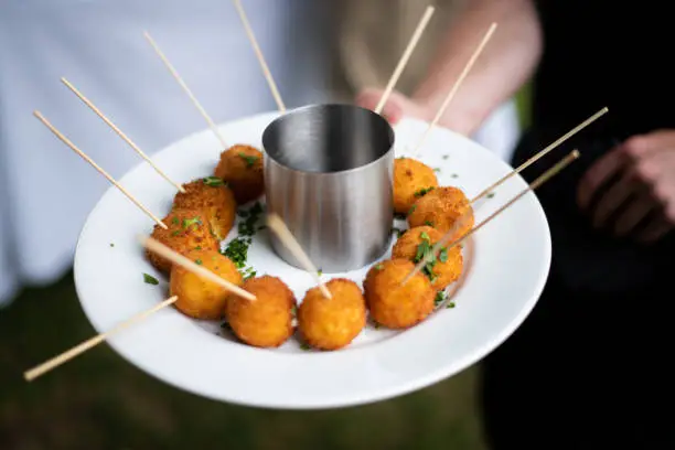 Photo of a plate of arancini being served as a passed appetizer by a catering company