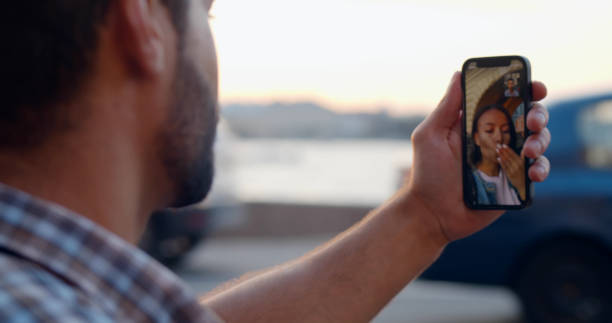 istock View over shoulder of young man doing video call using smartphone at city 1479199727