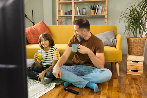 istock Man and his little boy watching TV at home 1479200205