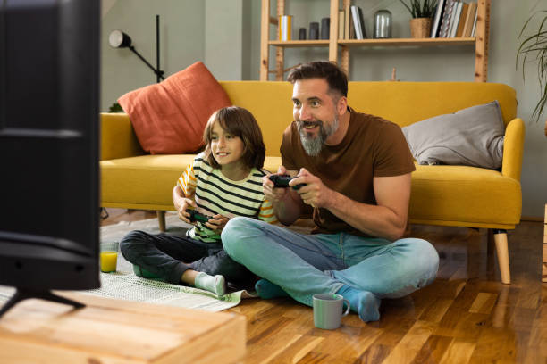 Gather and son playing video games and enjoying at home stock photo