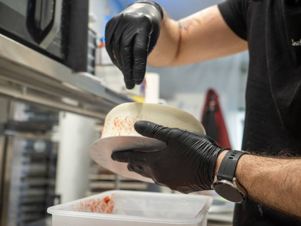 pastry chef designer sprinkling red sweets to a frosted icing cake