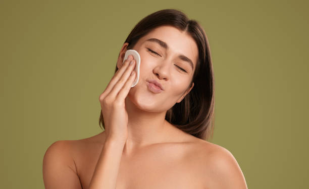 Happy female wiping face skin with pad stock photo