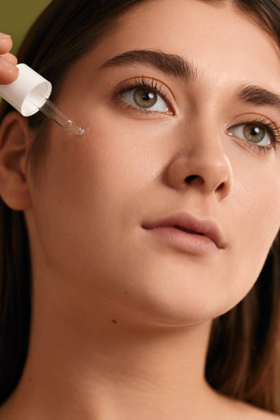 istock Crop young woman applying serum on face and looking away 1479201524