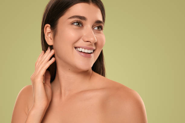 istock Delighted young lady touching long hair and smiling in green studio 1479201537