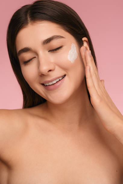 istock Smiling woman applying cream on cheek 1479201550