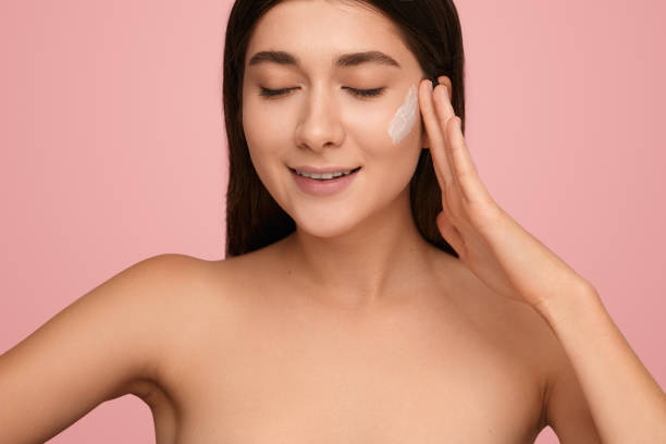 istock Glad woman smearing cream on cheek 1479201559